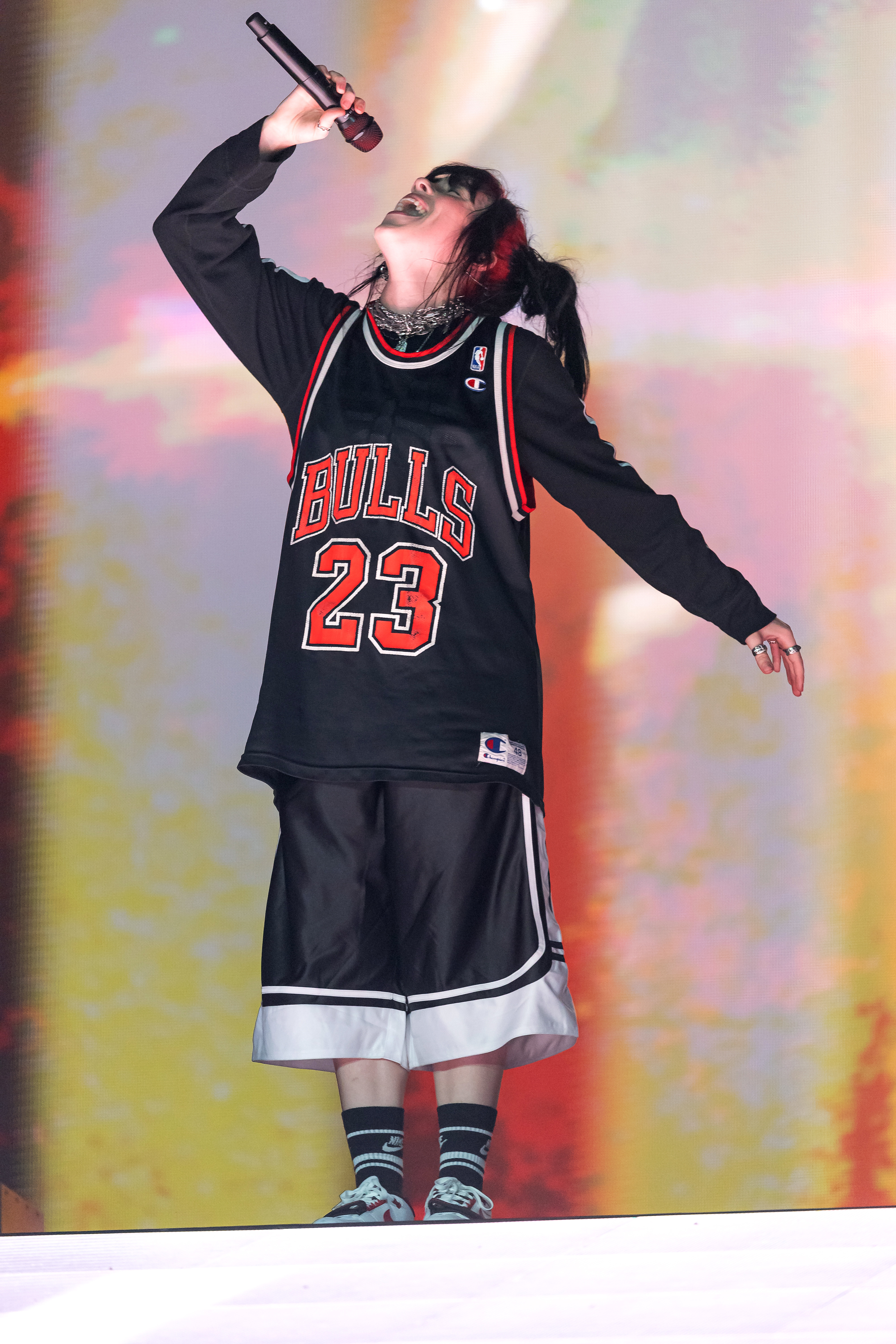 Billie performing onstage wearing a long-sleeved t-shirt, a Chicago Bulls jersey, and long basketball shorts