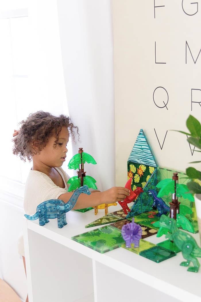 child model playing eith the printed magnatiles and dino figures