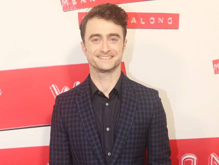 A closeup of Daniel Radcliffe smiling on the red carpet wearing a casual suit