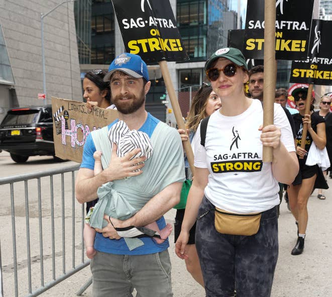 Daniel, who&#x27;s holding their son, walks alongside Erin as they particpate in the SAG-AFTRA strike