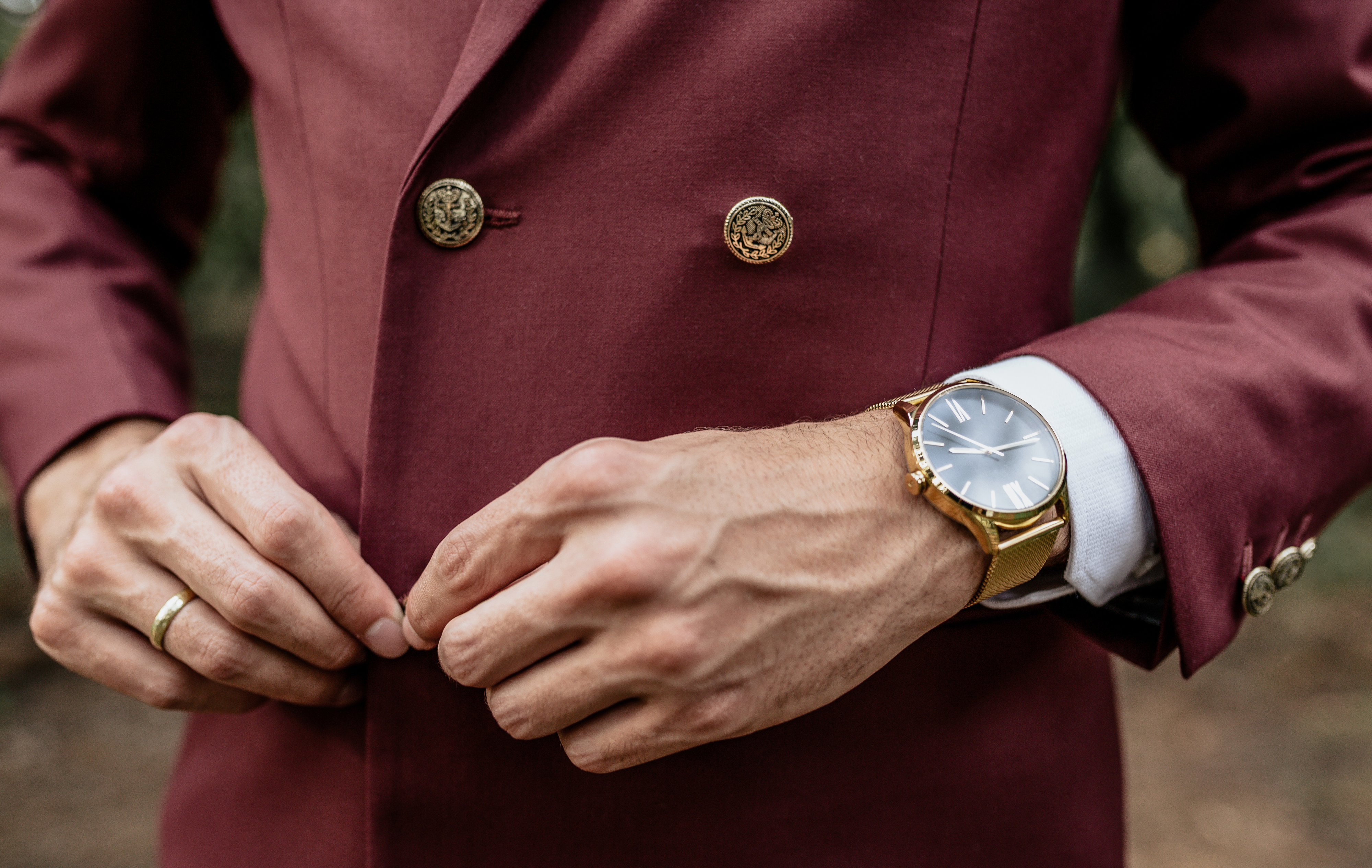 A man buttoning his jacket while wearing an expensive watch