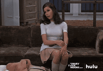 Mary Tyler Moore sighing, sitting back, and putting her hand to her face