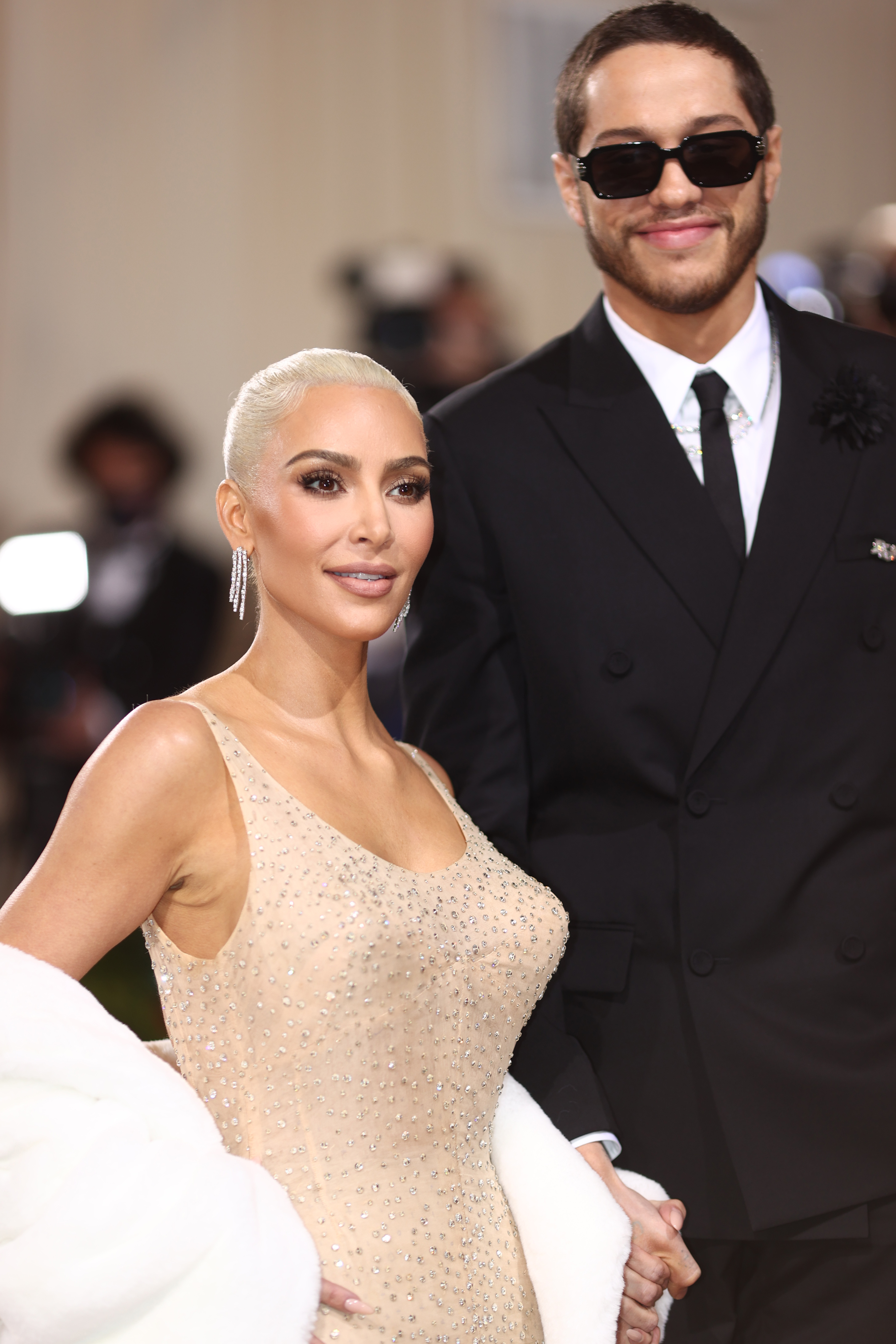 A closeup of pete and kim holding hands on the red carpet