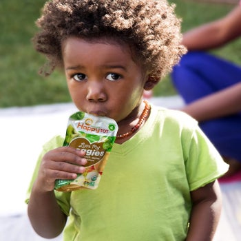 a toddler eating a happy tot pouch