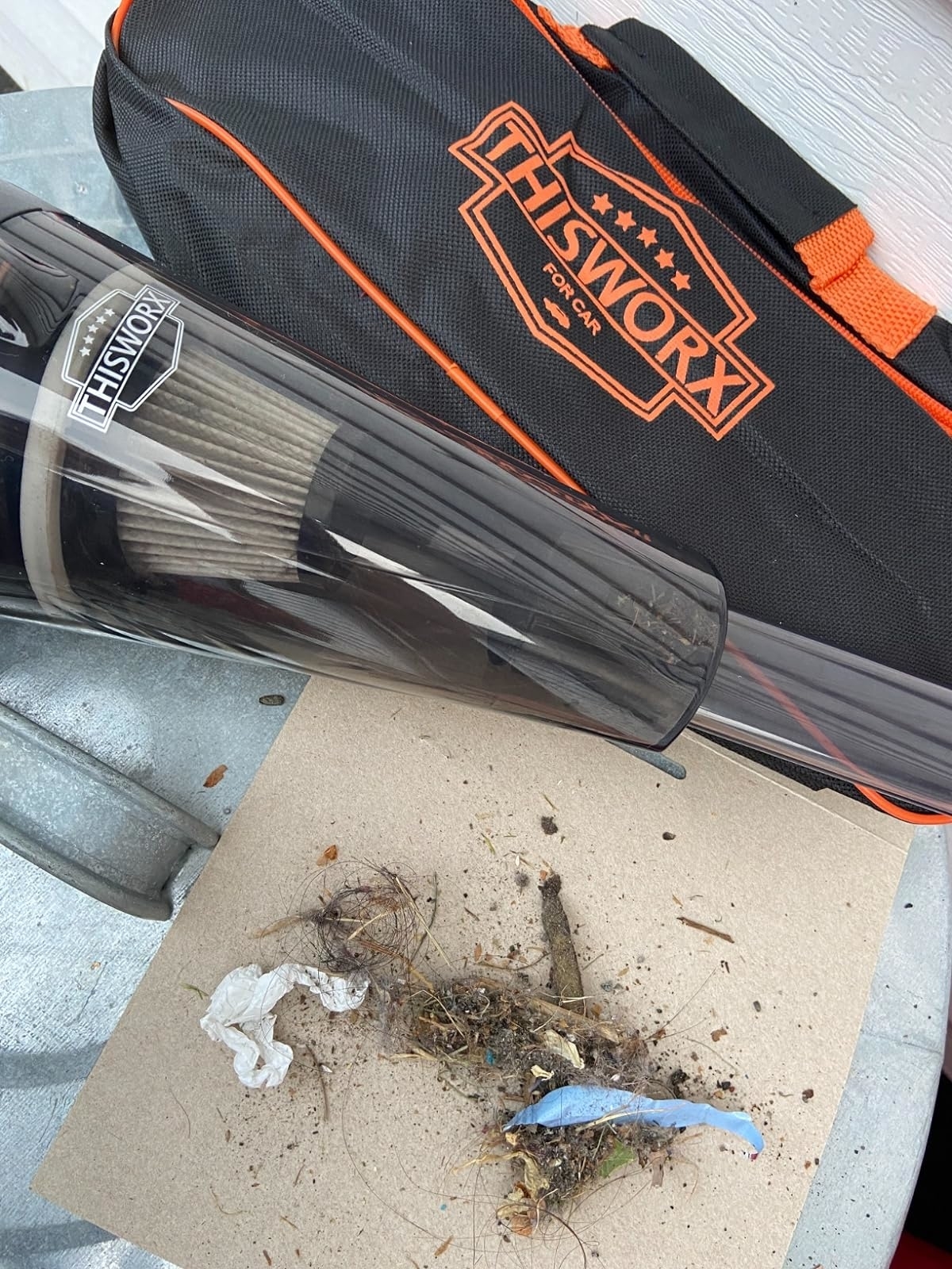 A reviewer&#x27;s vacuum with the pile of twigs and dirt the vacuum picked up