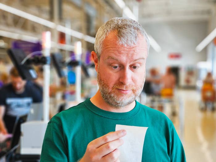 A man looking at his receipt in surprise