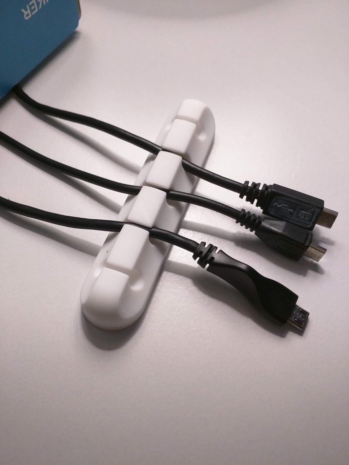 white cable organizer with black charging cables on desk