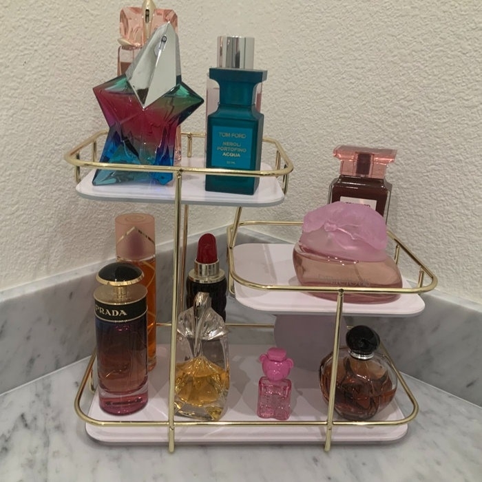 reviewer image of the white shelf with gold trim and perfumes on the shelves