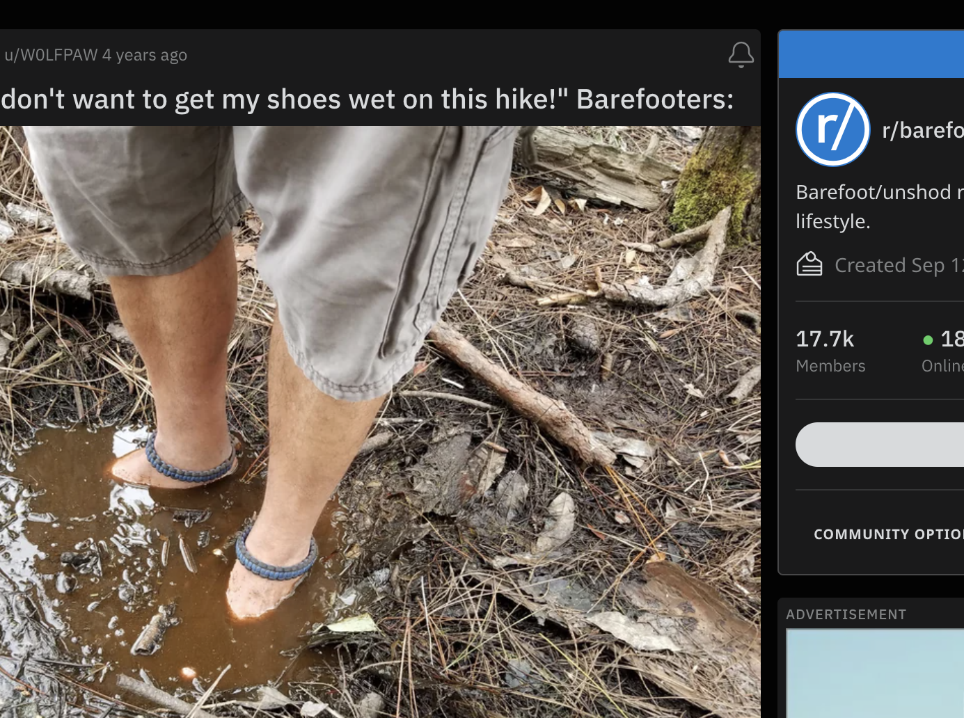 A man has his bare feet submerged in a muddy puddle