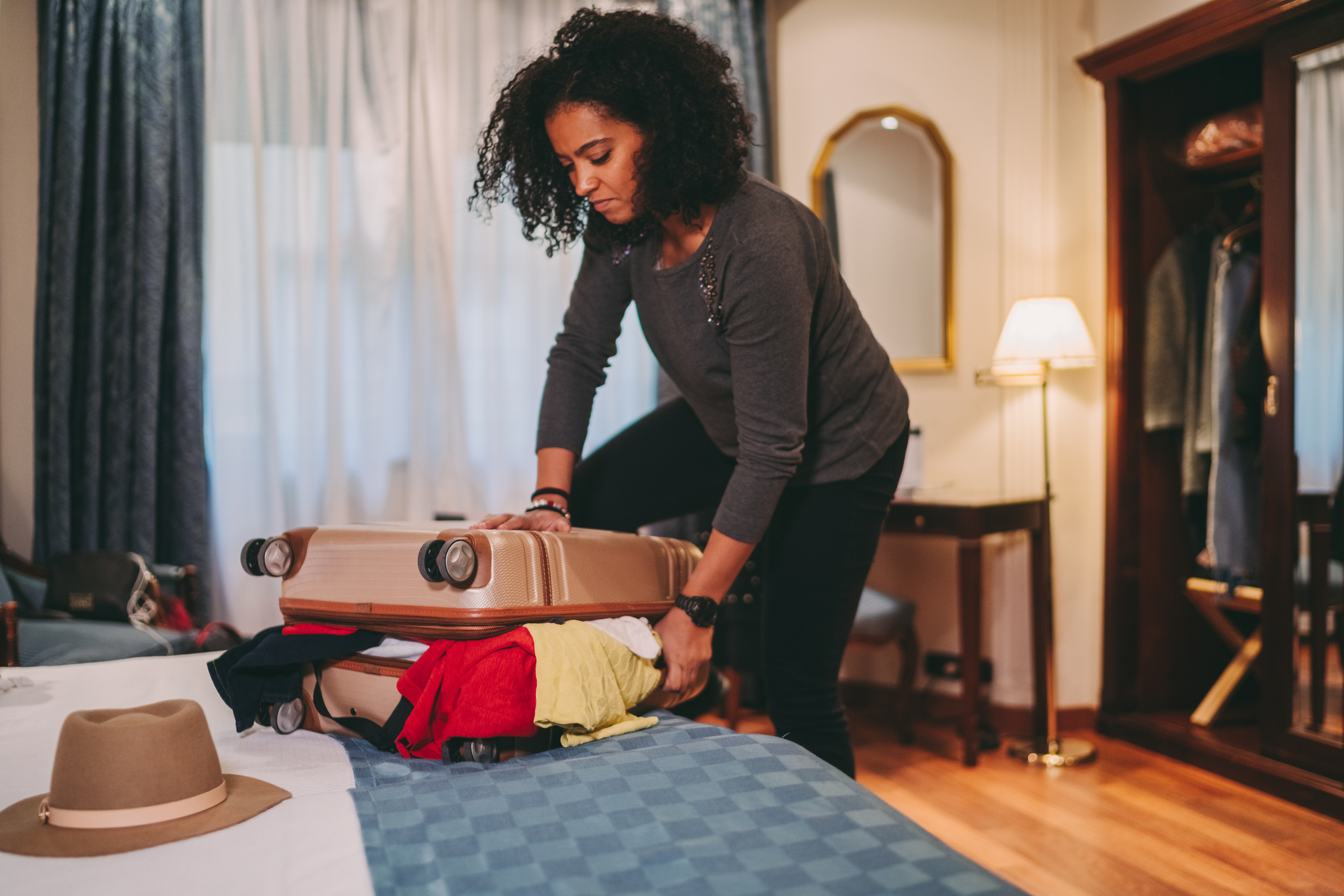 A woman packing up flustered trying to fit things into her suitcase