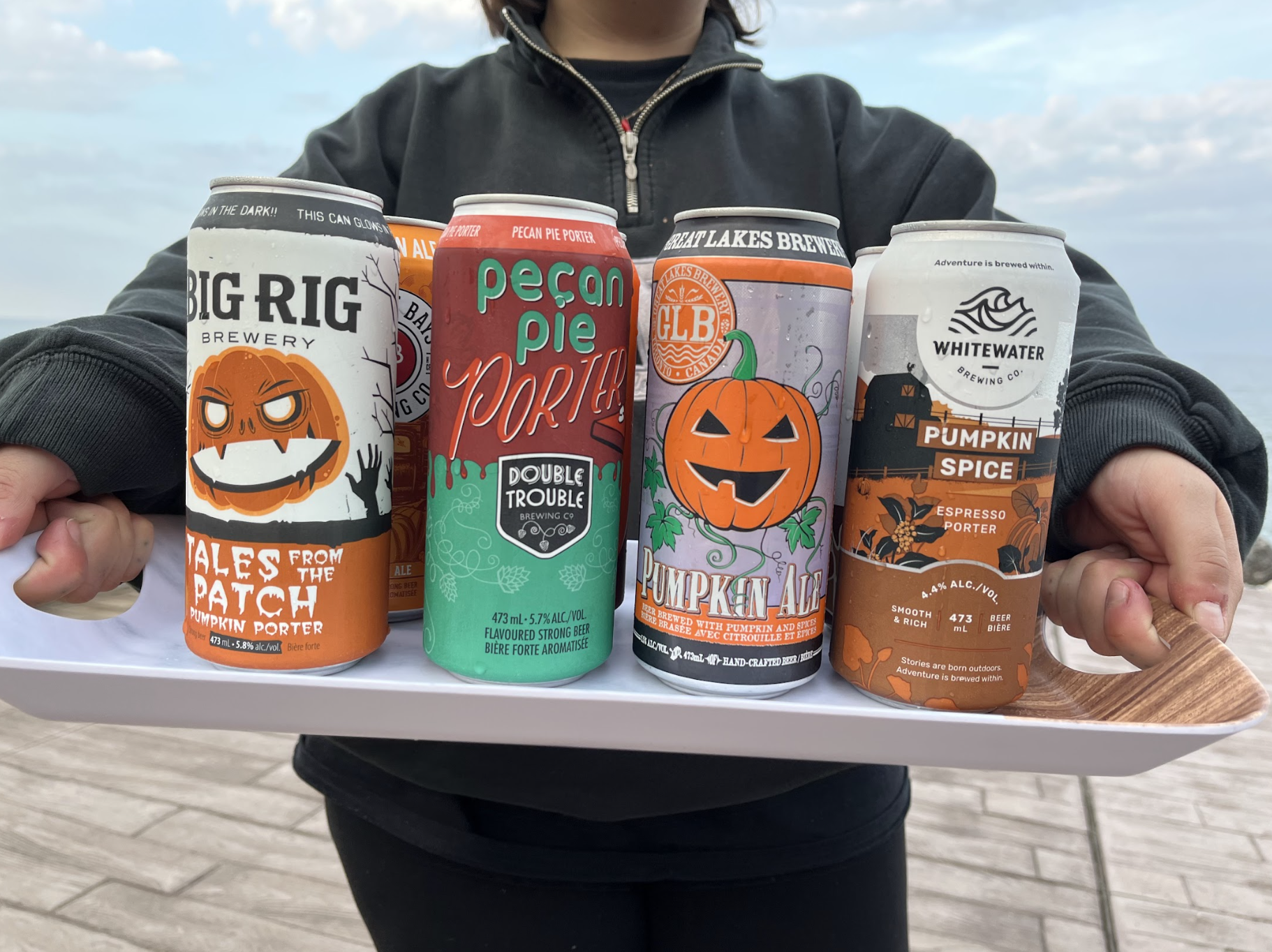 Someone holds up a tray of assorted pumpkin-spice beers.