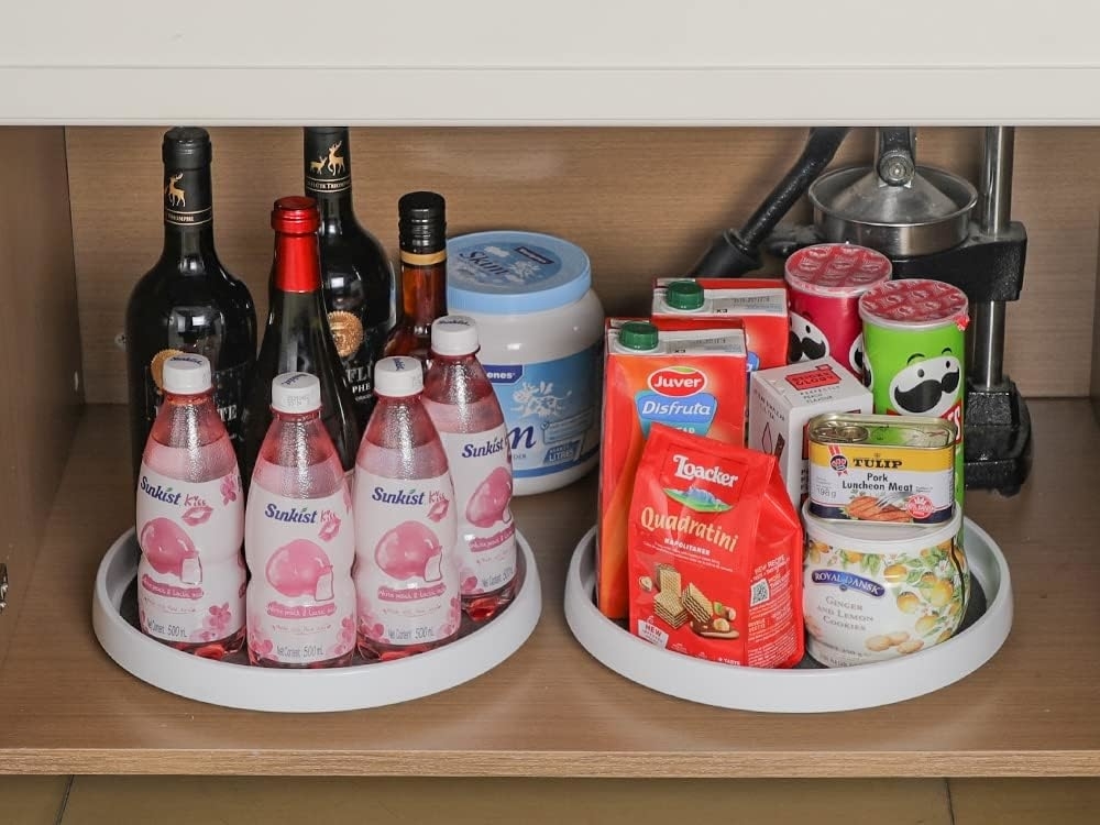 two lazy susans inside of a cabinet holding various drinks and snacks