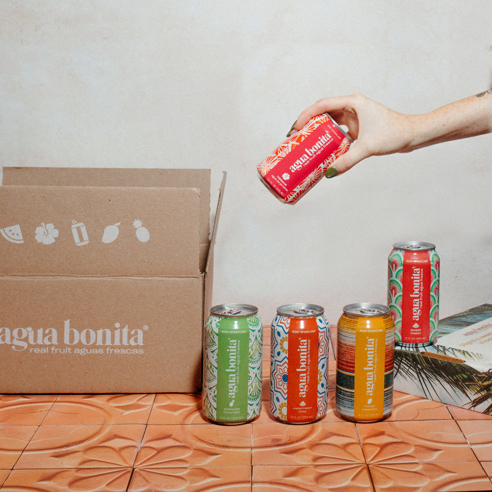 Hand grabbing a can of Agua Bonita from box