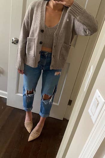 reviewer wearing the cardigan in a light grayish-tan color with jeans