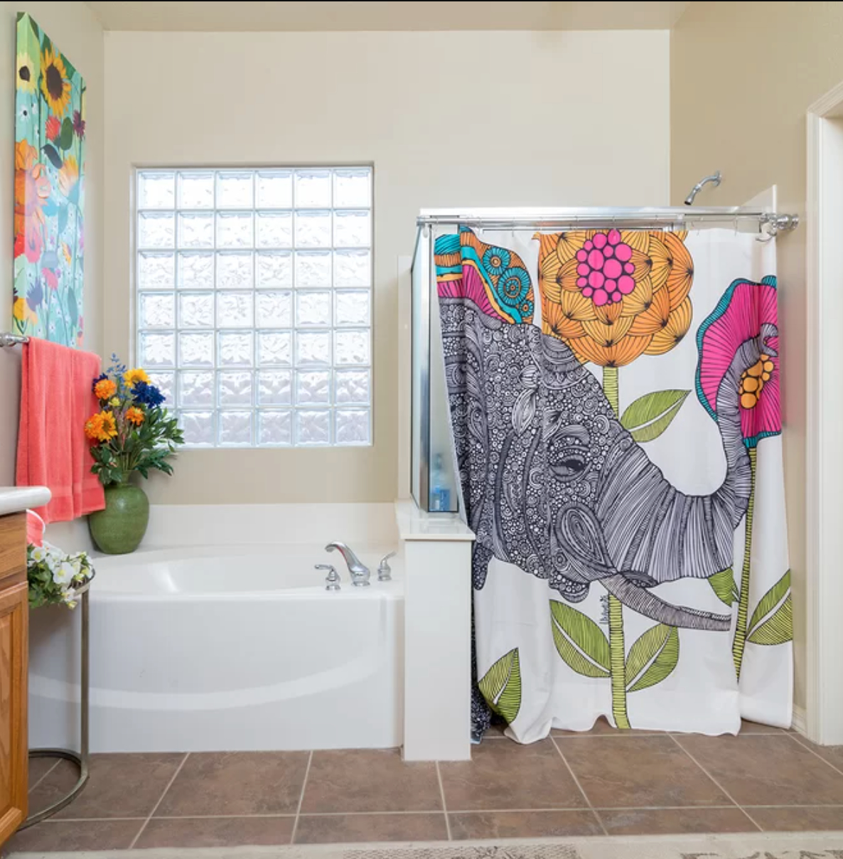 a bathroom with a tub and a shower curtain with a large elephant and flowers