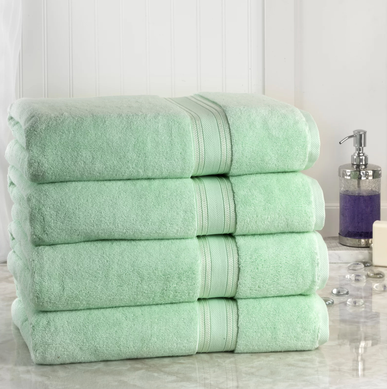 four soft jade green bath towels folded on the counter