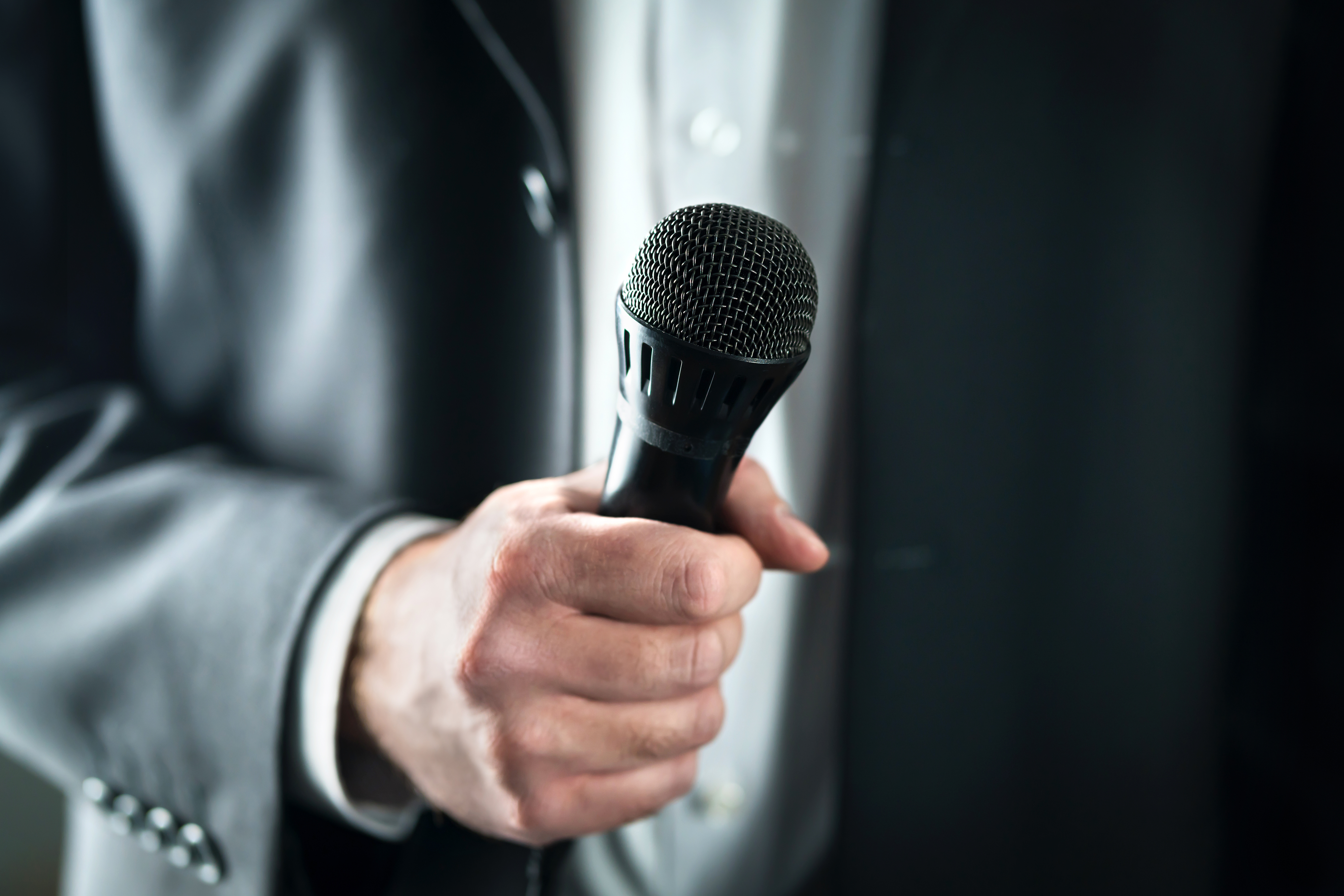 A person in a suit holding a mic