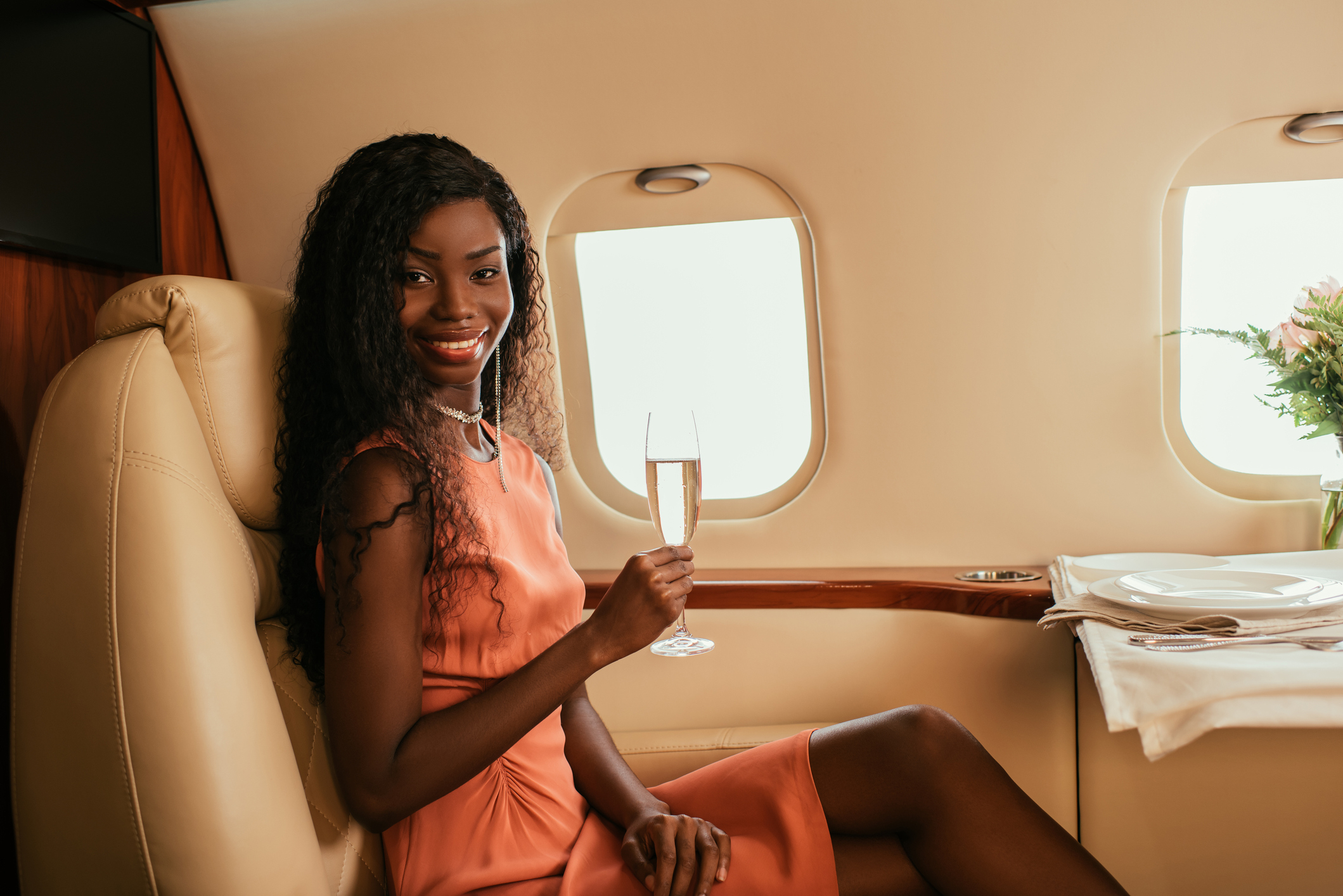 A woman holding a glass of champagne on a private plane