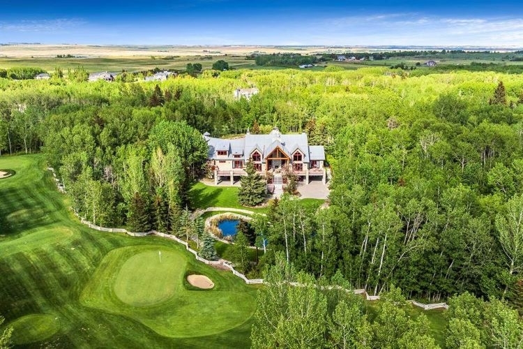 Cottage-like home is surrounded by thick forest on one side and a golf course on the other side.