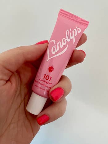an editor holding a pink tube of lanolips multi-balm strawberry