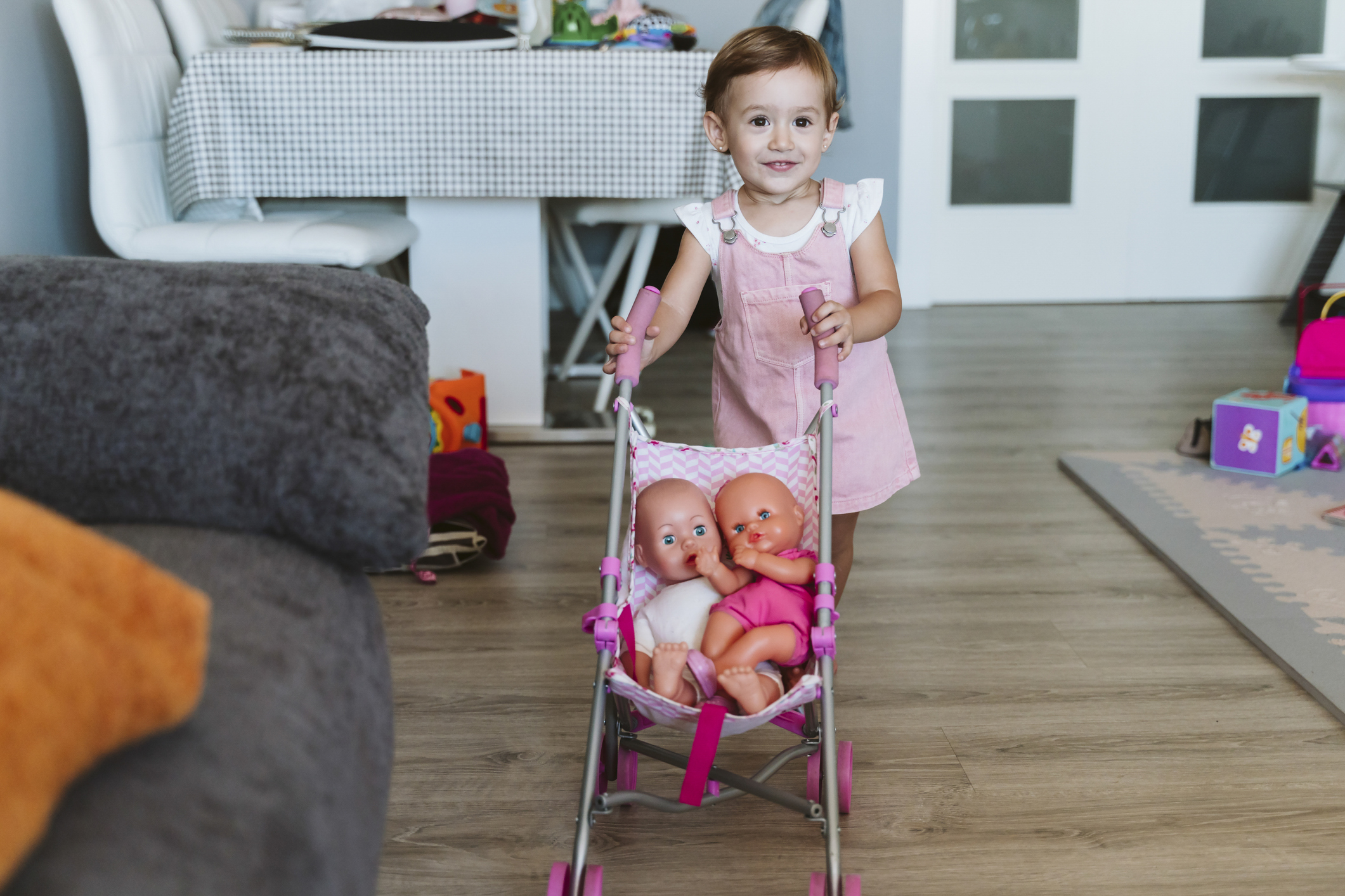 A little girl has two dolls in a stroller