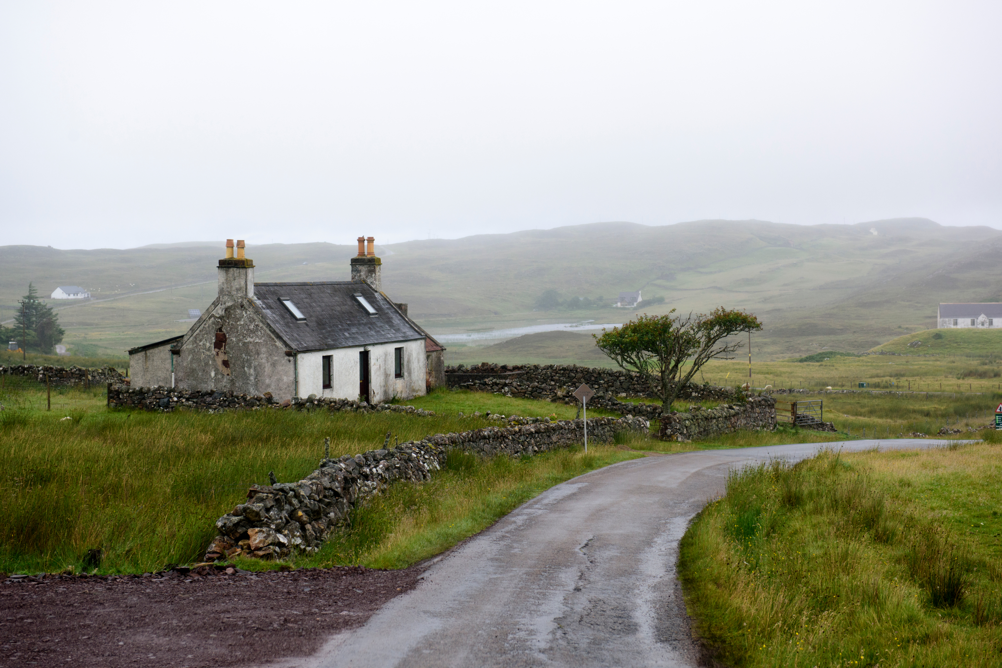 Abandoned white farmhouse with stone walls in the Scottish countryside