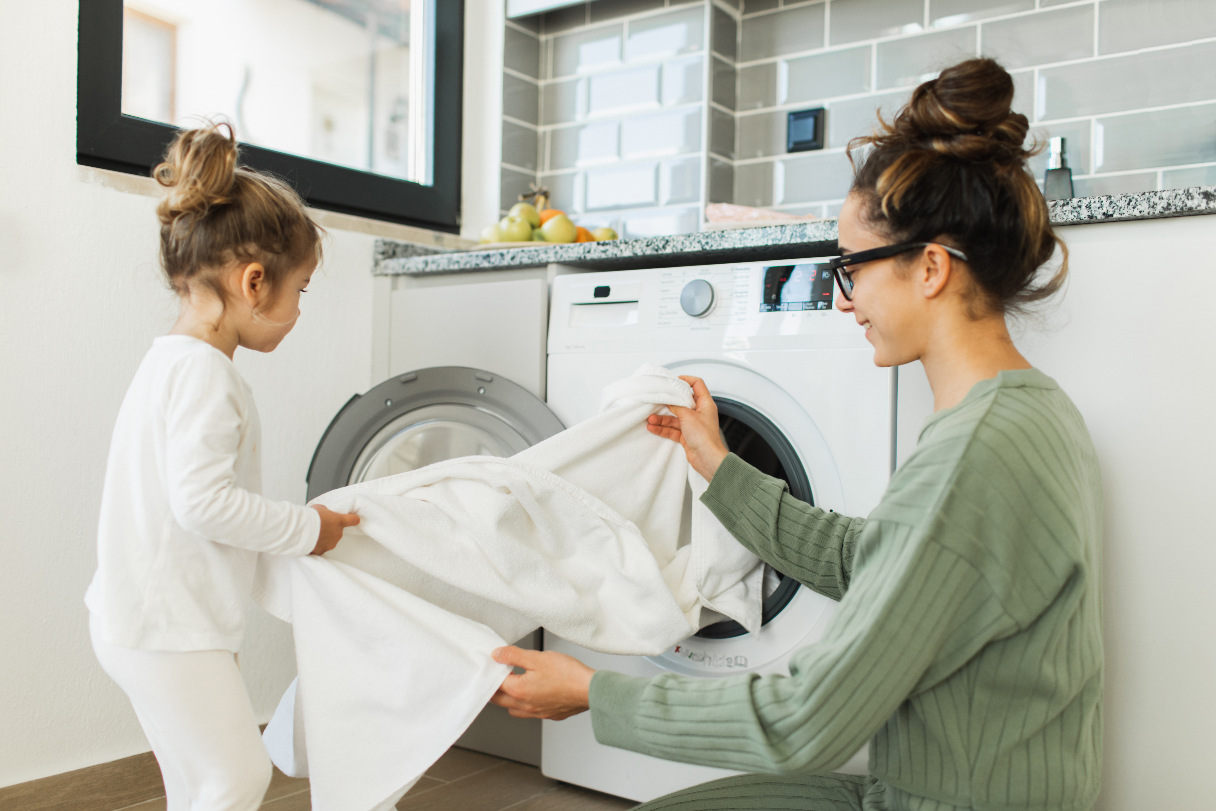 mother and young daughter taking laundry out of the dryer