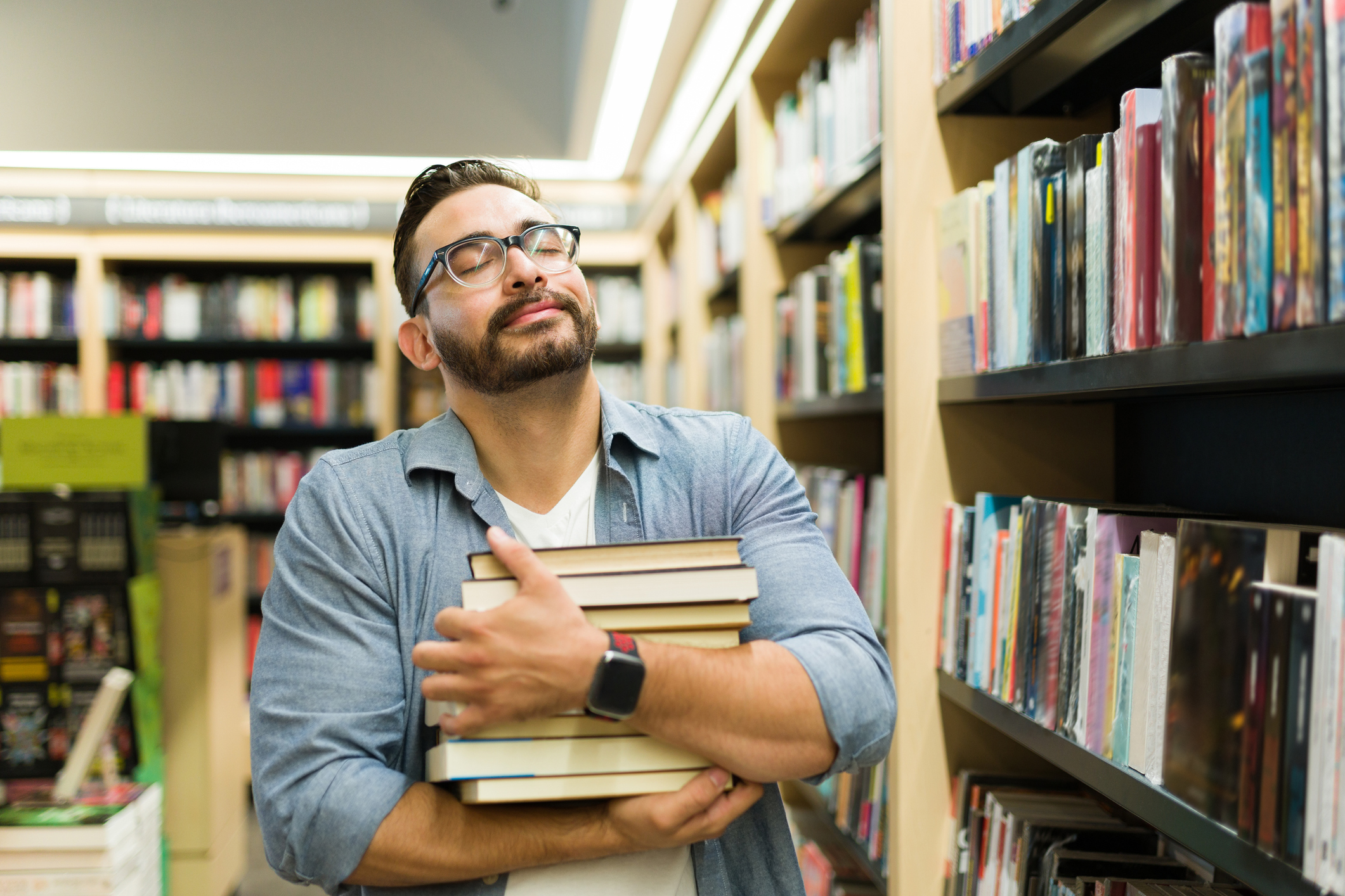 A man happily hugging a stack of books