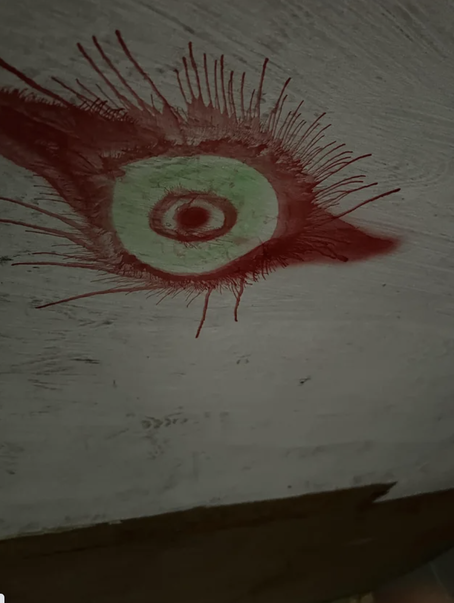 An eye/bullseye surrounded by red splotches of paint