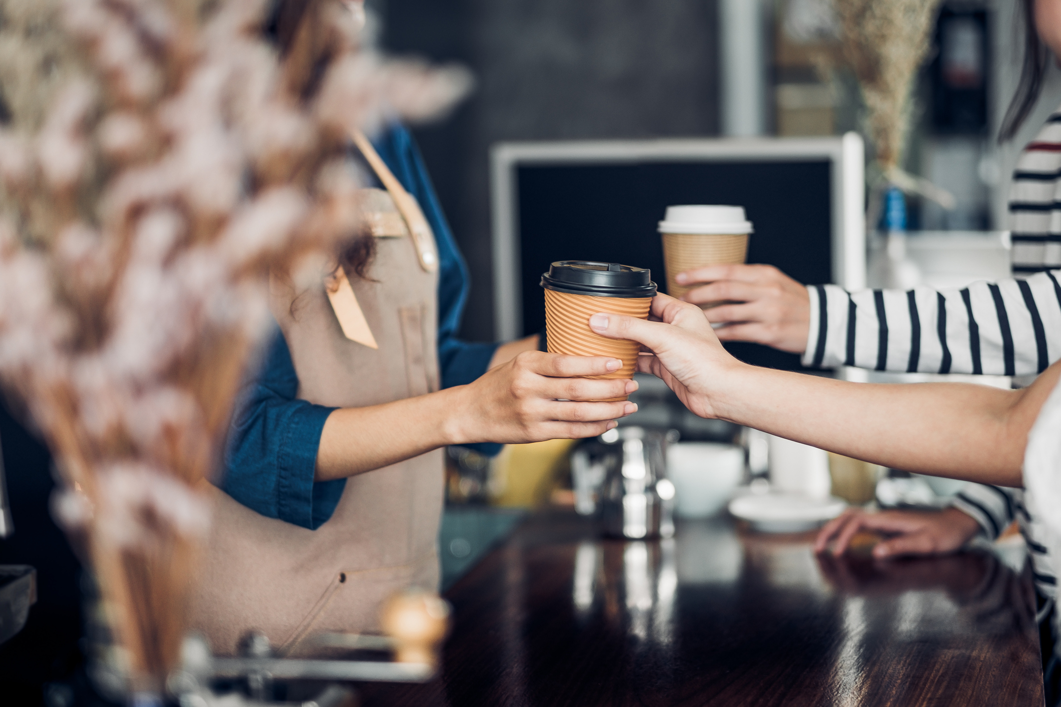 A barista handing coffee to a customer