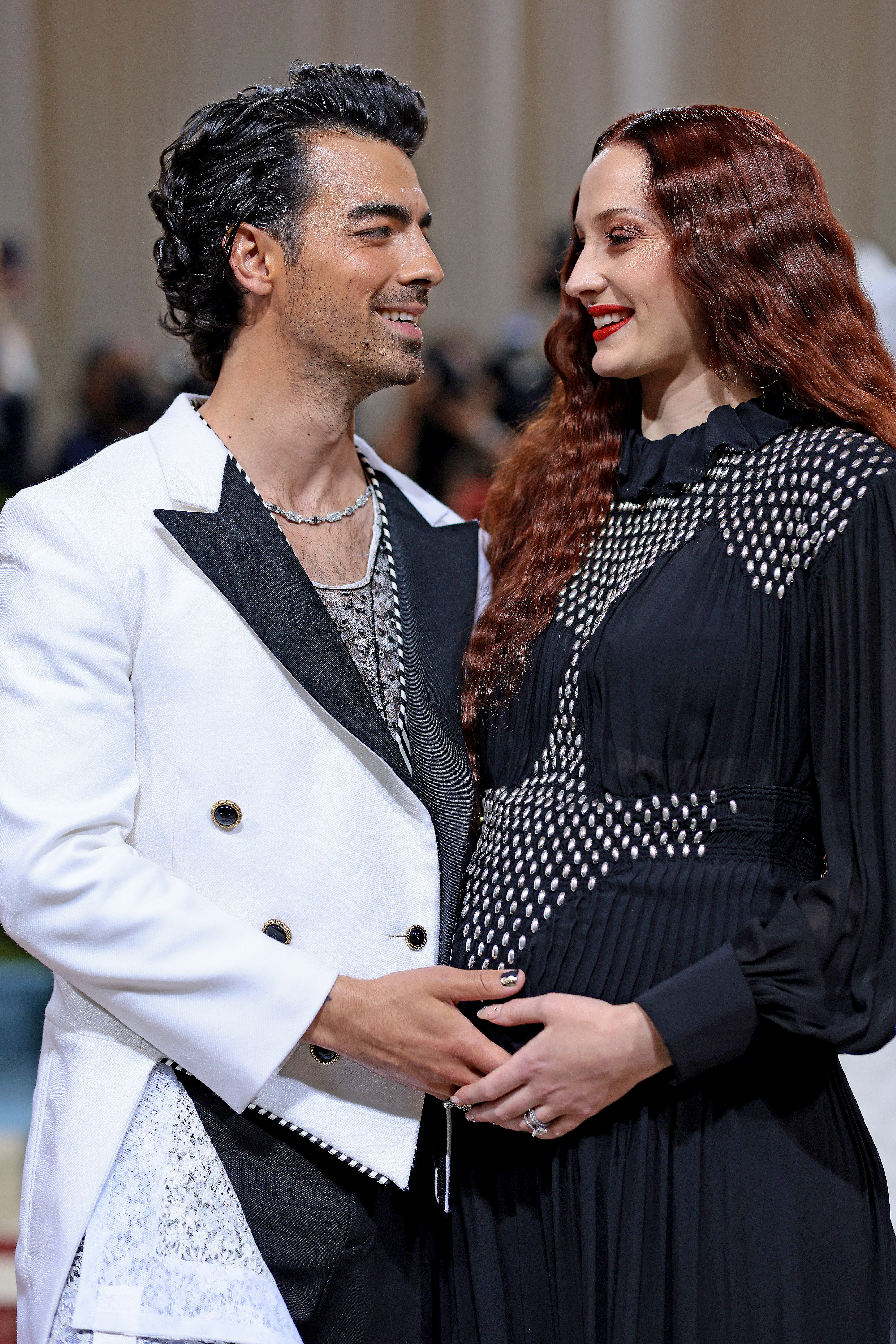 The former couple smiling at each other on the red carpet as they cradle her baby bump