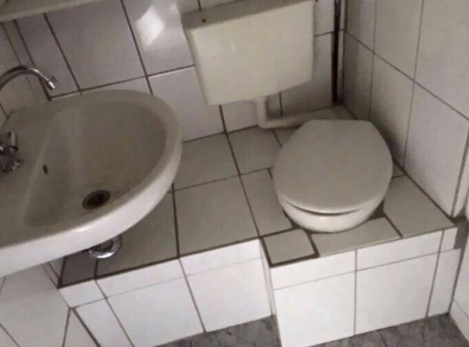 toilet covered in a tile seating area with the sink closeby