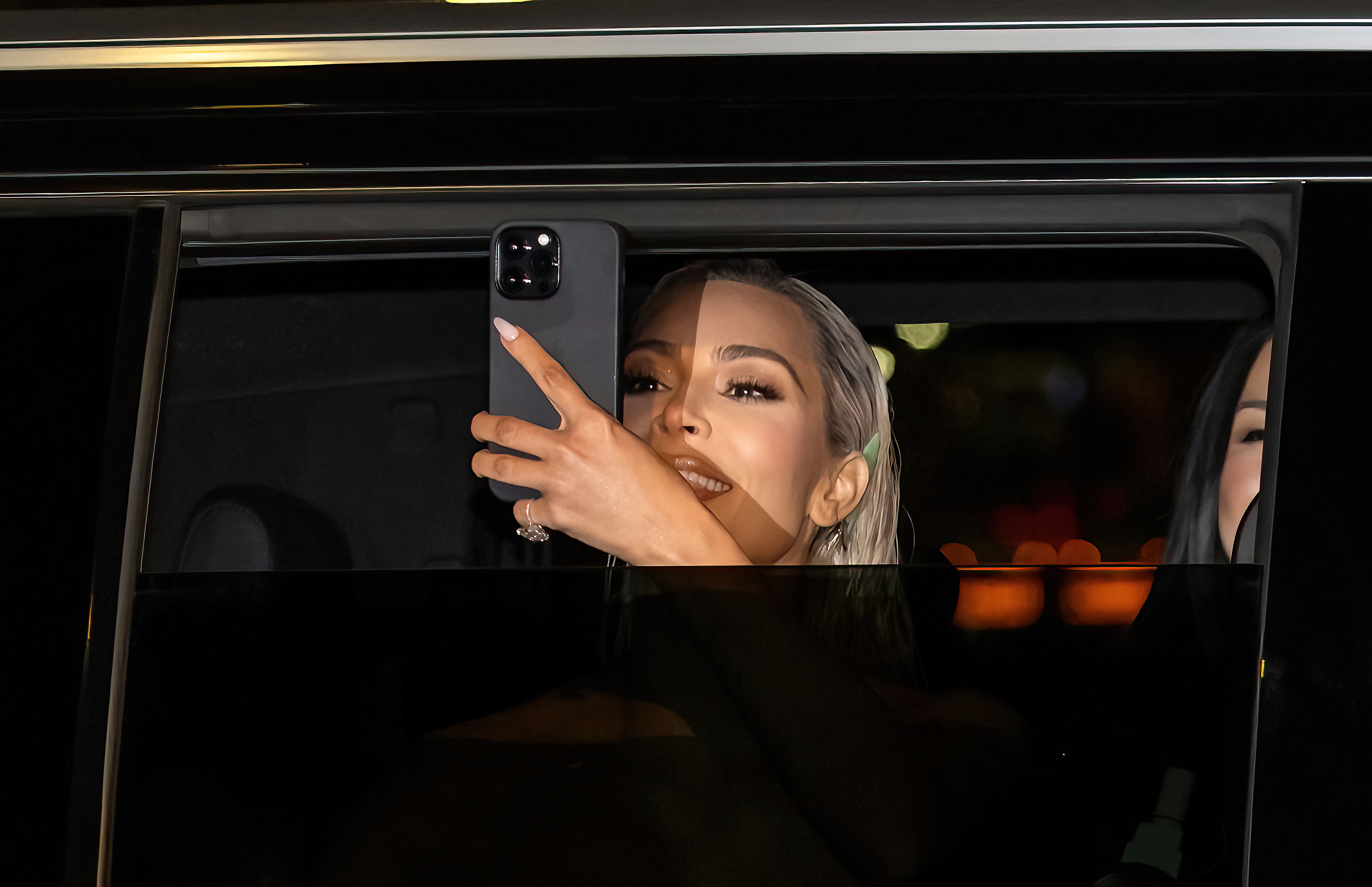 kim taking a photo from the car with the window only halfway rolled down