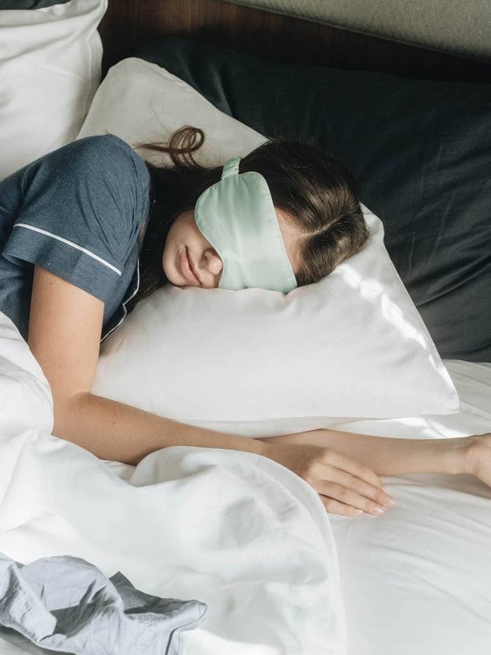 Model sleeping in bed with the green sleep mask.
