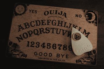 A planchette moves around a ouija board by itself