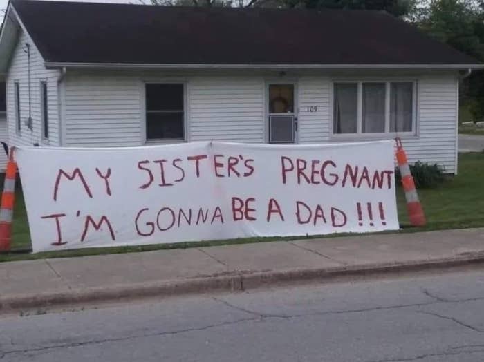 Words written in marker on a giant bedsheet say &quot;my sister&#x27;s pregnant, I&#x27;m gonna be a dad&quot;