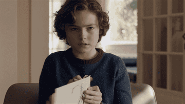 Will from Brahms The Boy 2 holding up a handwritten paper that says I&#x27;d like to go now