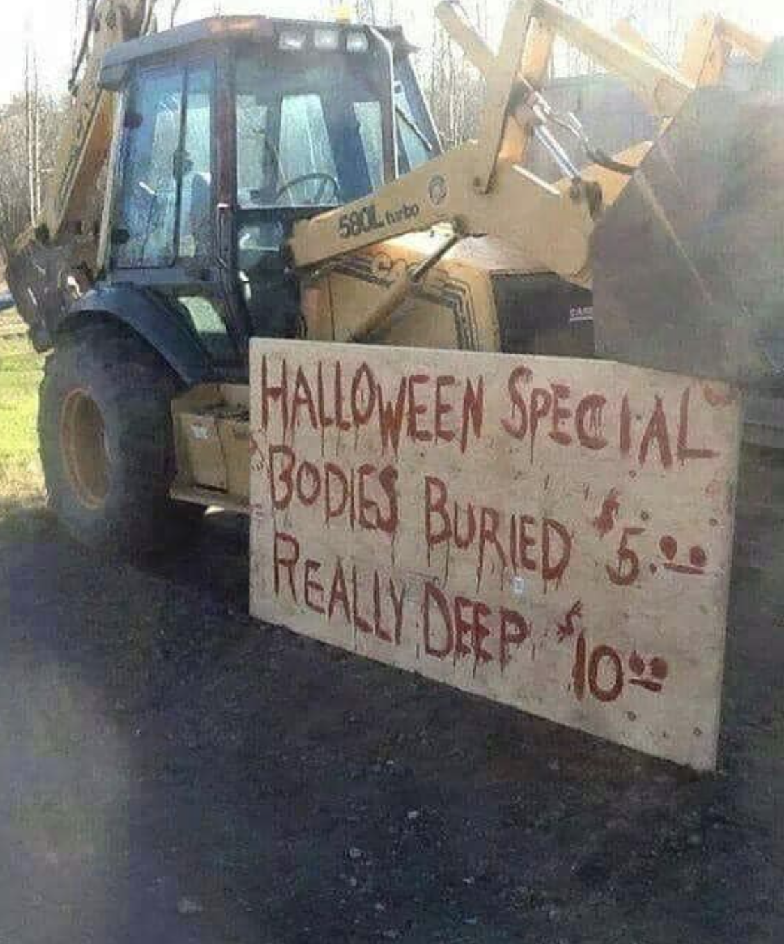 A wooden sign next to a large construction vehicle says "Halloween special: bodies buried $5, really deep $10"