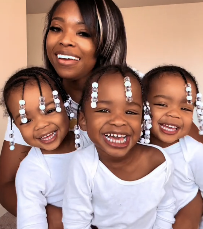 Dee posing with her three triplet daughters in a video