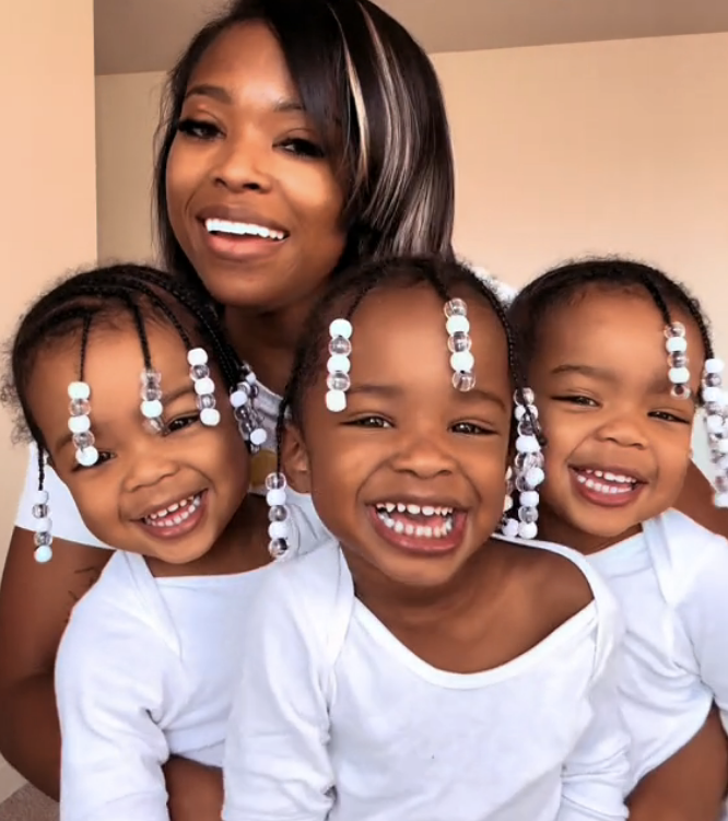 Dee posing with her three triplet daughters in a video