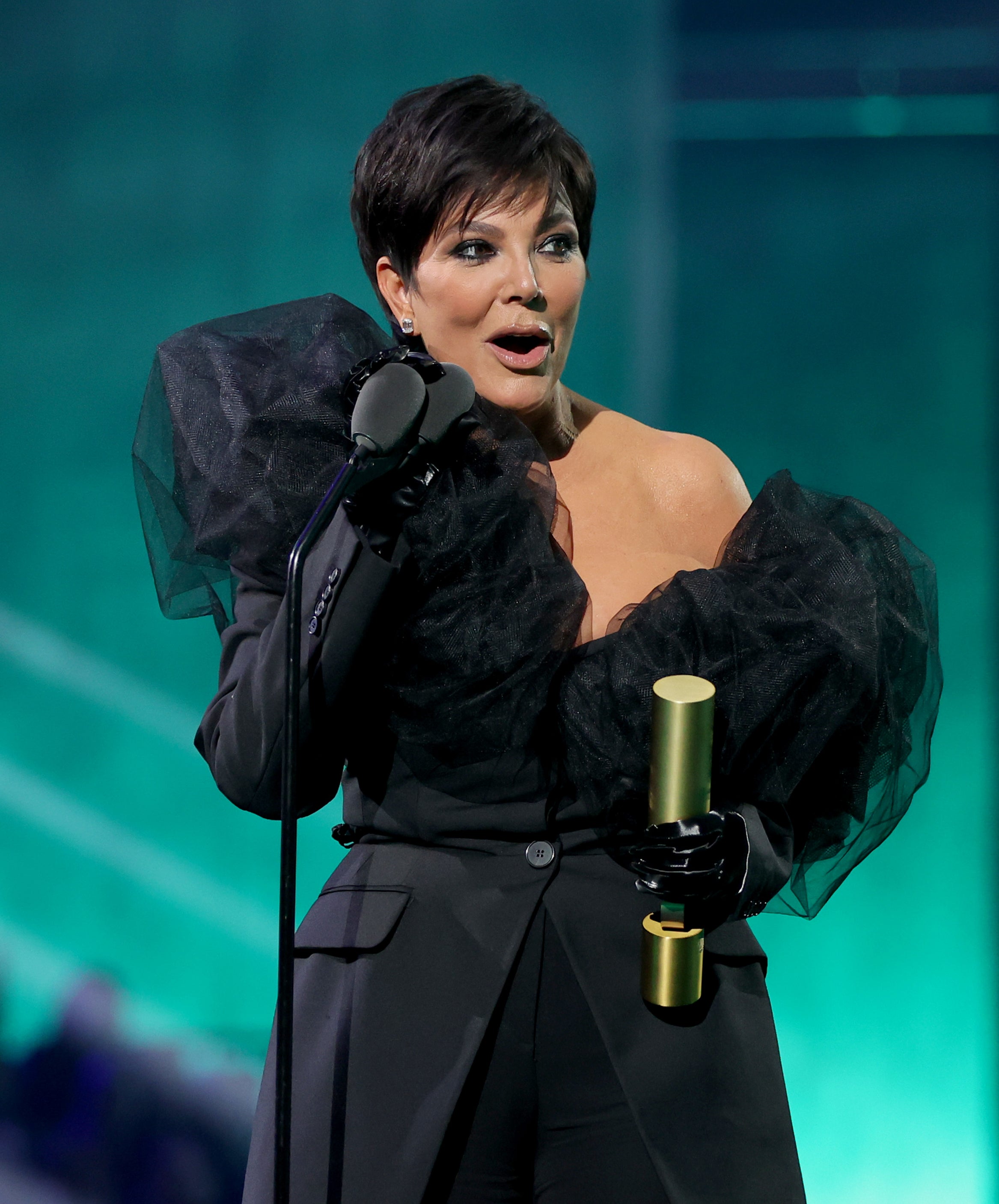 Close-up of Kris onstage holding an award