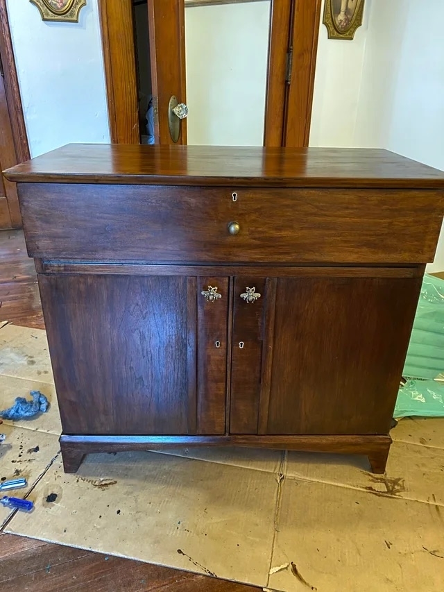 The bar cabinet after with a dark wood finish and bee knobs