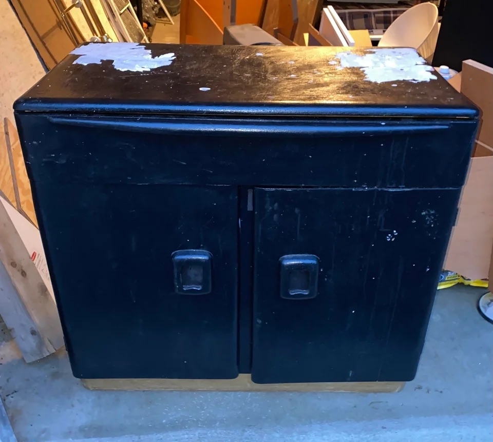 A before image of a cabinet covered in dark paint