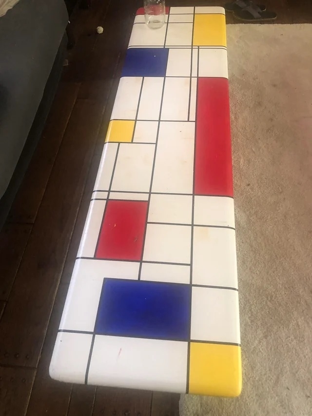 A before image of a long coffee table with Mondrian-type colorful abstract squares