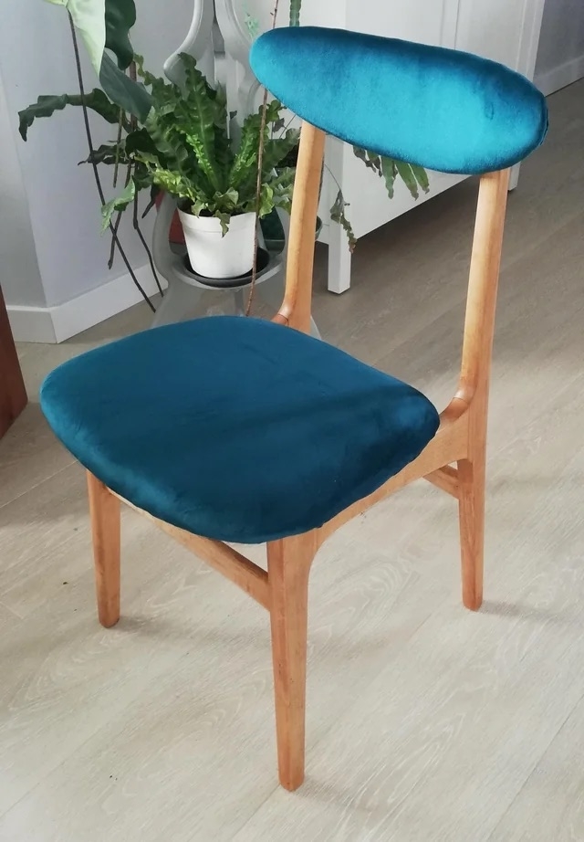 The chair after with a light wood frame and blue velvet cushion
