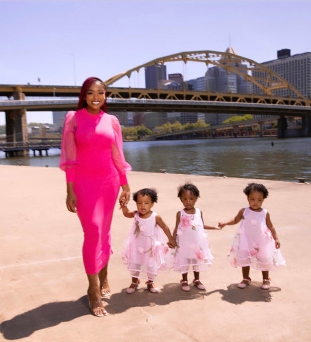 Dee posed with her triplets in front of a city skyline and bridge