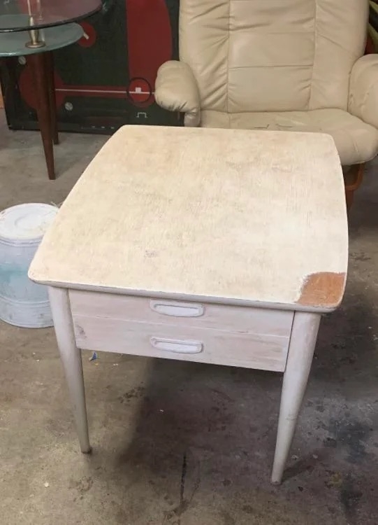 A before image of a wooden side table covered in white chalk paint