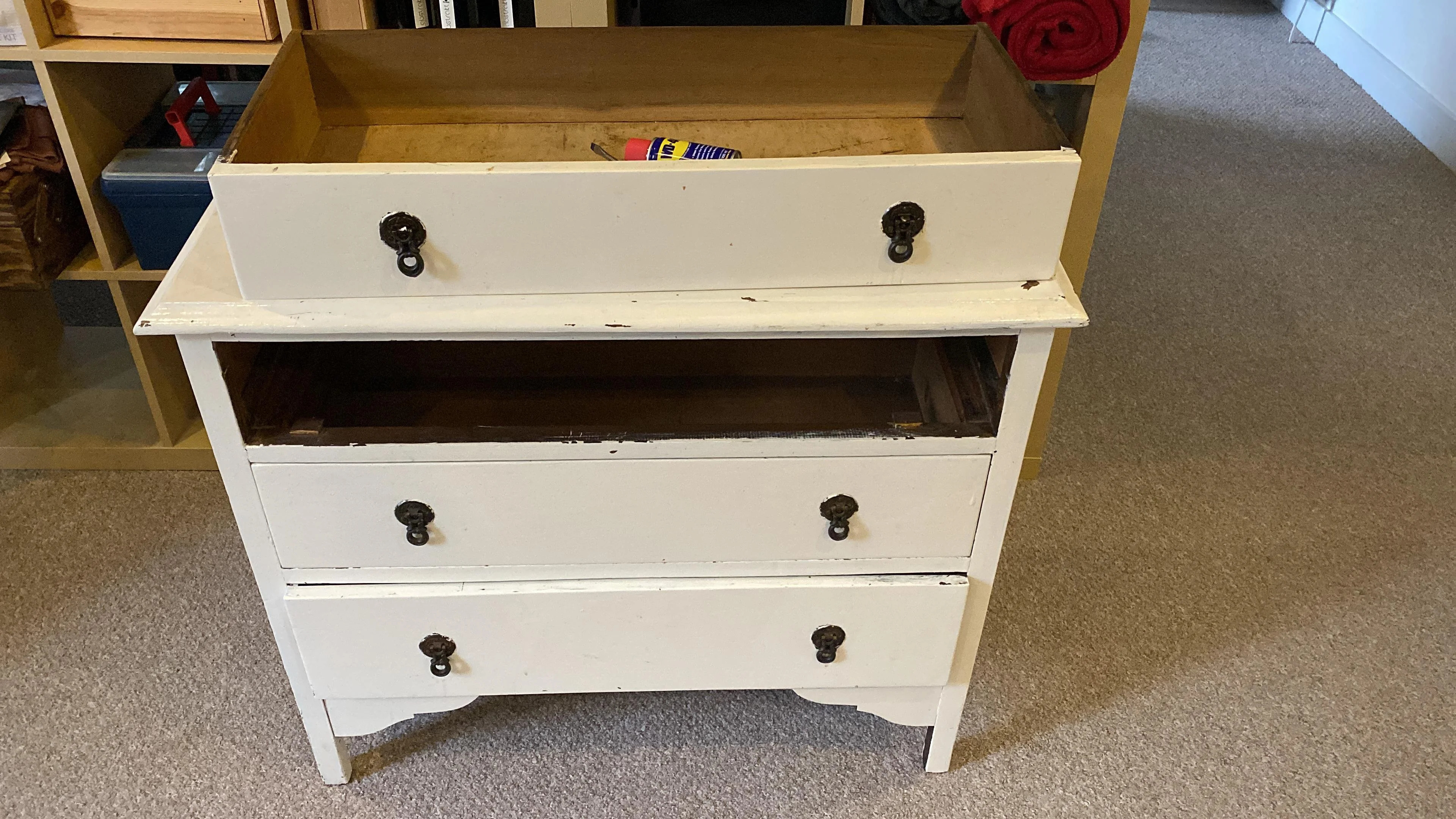 A before image of a beat-up white dresser
