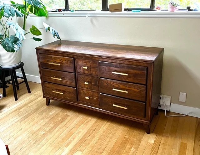 The dresser after with a dark wood finish and brass handles