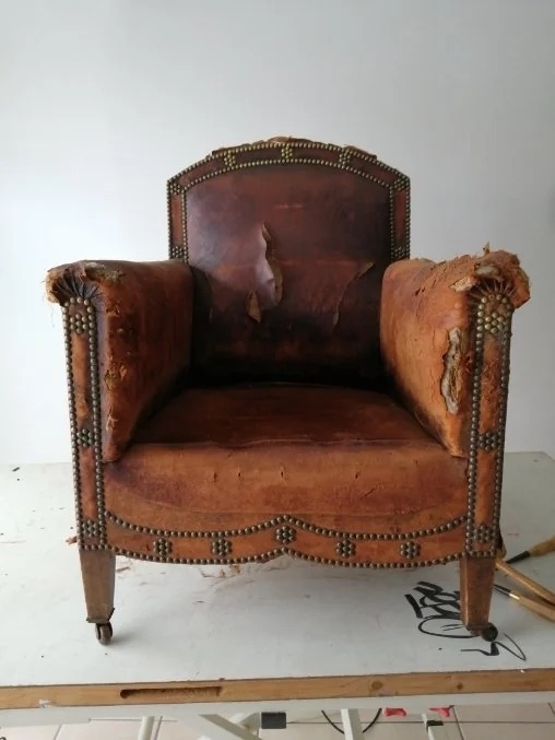 A before image of an armchair with badly peeling and frayed leather